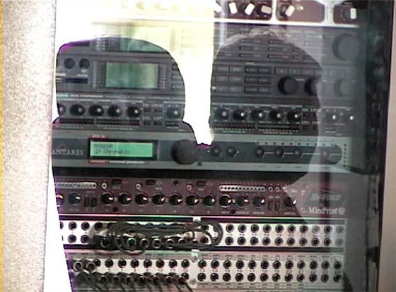 Das Rack hinter Glas. Oben liest man Antares, darunter MindPrint. In der Scheibe spiegelt sich Peter Fischer.